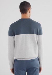 Herrtröja med ett färgblockeringsdesign, med en mörkblå överdel och en ljusgrå nederdel, tillverkad av mjukt stickat material.