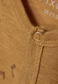 Vêtement en coton de couleur brun chaud avec une finition texturée. Présente une petite fermeture à bouton et un motif subtil près de l'encolure. Étiquette de taille visible.