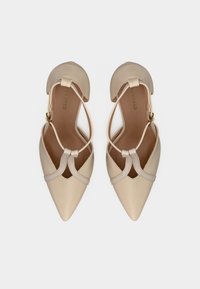 Escarpins en satin beige à bouts pointus avec découpes, brides à la cheville et texture lisse. L'intérieur comporte le logo de la marque et une semelle intérieure rembourrée.