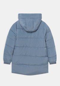 Fodrad jacka i ljusblått, med huva, ribbade ärmslut och horisontell sömnad för isolering. Slät, glänsande tygtextur.