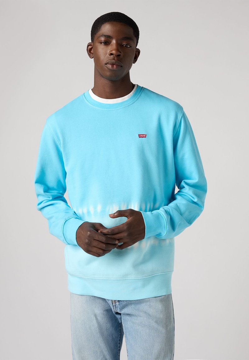 Lichtblauwe sweatshirt met een verloop naar wit, gemaakt van zachte stof. Ronde hals ontwerp met een klein rood Levi's logo op de borst.