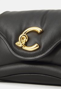 Sac en cuir noir avec un design rembourré, fermoir métallique doré en forme de lettre 'C' et détails de couture subtils le long des bords.