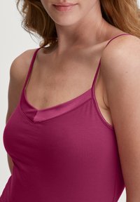 Fitted hemdtop in diep magenta, met dunne verstelbare bandjes en een v-hals, gemaakt van soepele, rekbare stof.