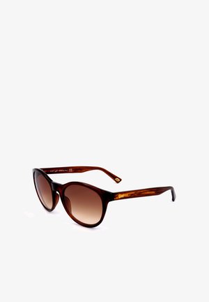 Occhiali da sole a forma di occhio di gatto con montatura in tartaruga e lenti sfumate marroni, con aste curve, mostrati inclinati su uno sfondo bianco.