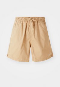 Světle hnědé sportovní šortky s elastickým pasem a šňůrkou, s malým logem Nike na dolní části levé nohy.