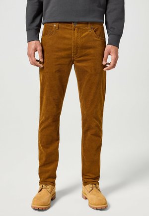 Pantaloni in corduroy marrone con design a gamba dritta, dotati di tasche frontali e chiusura con bottone in metallo, abbinati a stivali beige.