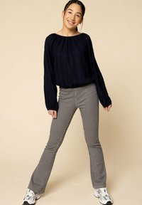 Marineblauw textuur langemouwen top met een geplooide halslijn, gecombineerd met grijs gestreepte flared broek en witte sneakers.