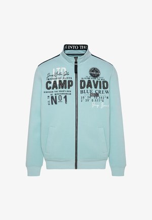 Lichtblauwe rits-sweater gemaakt van katoen. Voorzien van een staande kraag, zwarte accenten en gedrukte graphics in verschillende lettertypen op de voorkant.