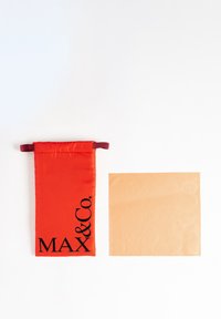 Funda de tela roja con impresión negra "MAX & Co." en un lado. Al lado hay una tarjeta beige con "MAX" y "Co." en relieve.