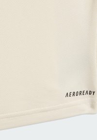 Hellbeige Sportshirt aus strukturierter Stoffqualität, mit dem schwarzen Aufdruck der Marke "AEROREADY" nahe dem Saum.