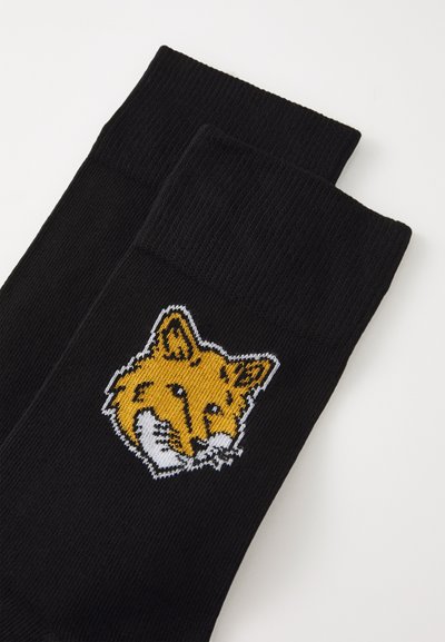 Black socks with ribbed texture featuring a yellow and white fox design embroidered on the front.