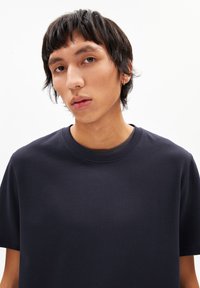 T-shirt en coton bleu marine avec un col rond, des manches courtes et une texture lisse. Design simple sans motifs ni accents visibles.