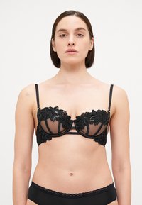 Schwarzer Spitzen-BH mit floralen Motiven, durchsichtigen Netzbechern, Unterwäschesupport und dünnen verstellbaren Trägern. Dazu gehört ein passender schwarzer Slip.
