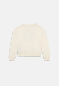 Sweatshirt court de couleur crème avec des manches longues, des poignets côtelés et une couture en forme de V au dos, fabriqué à partir d'un tissu doux et texturé.