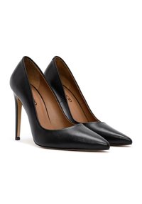 Zapatos de tacón alto de cuero negro con puntera afilada, textura suave y un tacón delgado tipo estilete. El interior tiene un forro en color marrón claro.