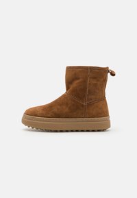 Braune Wildleder-Ankle-Boots mit runder Zehenform, genähten Details, weicher Textur und einer Gummisohle mit kleinen Traktionsspitzen.