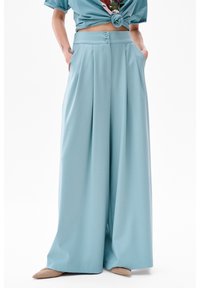 Pantalons larges bleu clair avec taille haute, deux boutons et poches latérales. Tissu doux au toucher soyeux, conçu pour le confort.