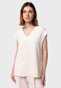 Halenka s výstrihom do V, bez rukávov, vyrobená z mäkkej, štruktúrovanej off-white látky. Má voľný strih a nenápadný detail loga na leme.