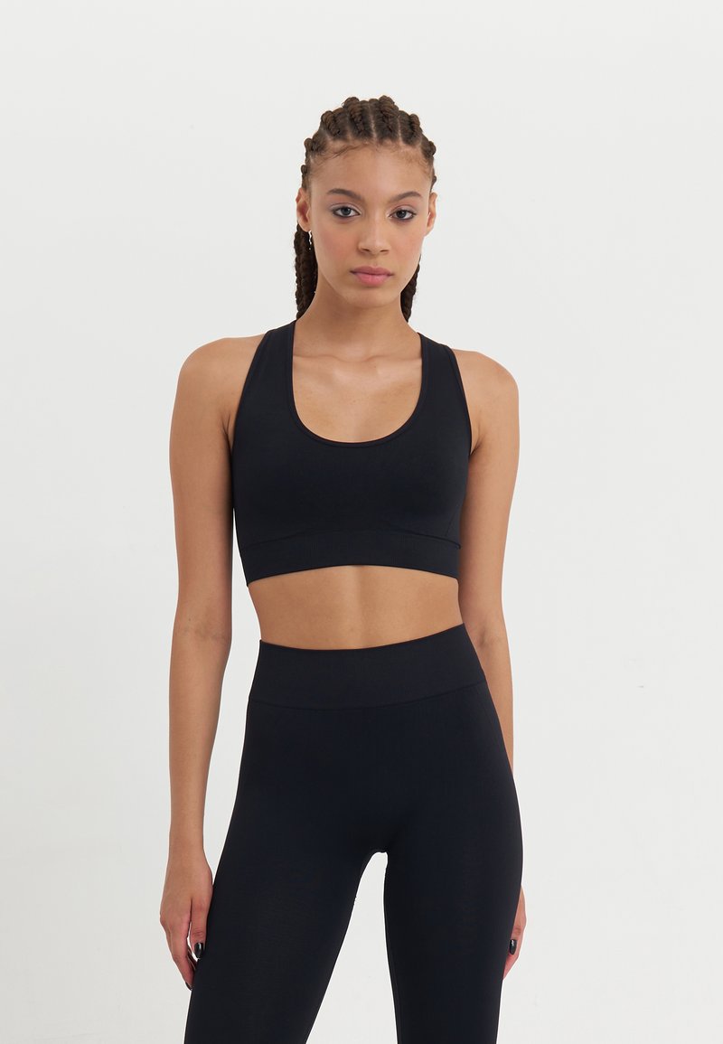 Black sports bra and high-waisted leggings made from stretchy, smooth fabric, featuring a scoop neckline and minimal stitching detail.