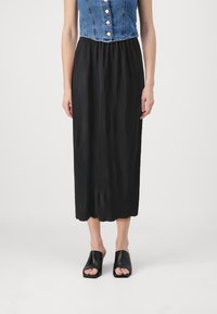 Svart plisseret midi-nederdel med en glat tekstur og ribbet design. Parret med åbentåede sorte slide-sandaler. Denimtop delvist synlig.