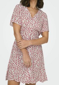 Kukkakuvioinen mekko lyhyillä hihoilla, kevyt kangas, vaaleanpunainen tausta, pieniä punaisia kukkia, V-pääntie, napitus edessä, levenevä hame.