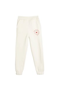 Cremefarvede sweatpants lavet af blødt stof. Har elastisk talje, sidelommer og et trykt design med et hjerte på venstre ben.