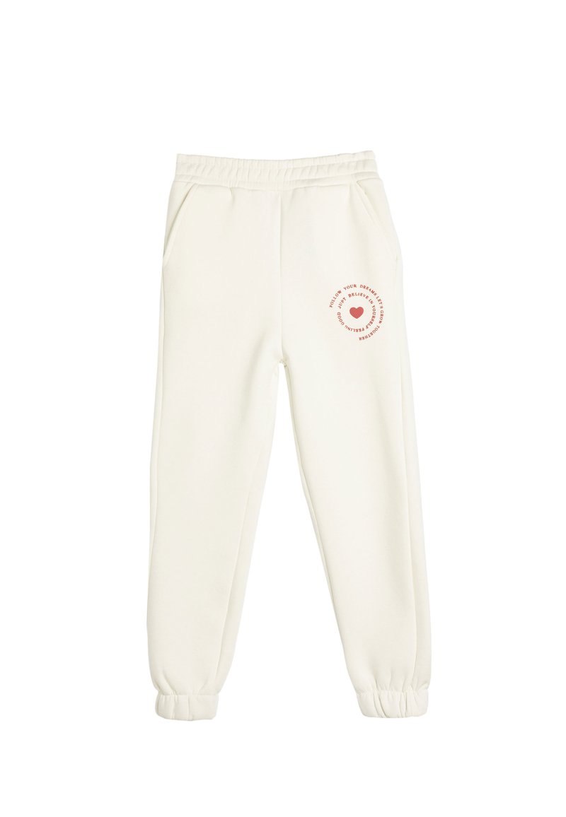 Cremefarvede sweatpants lavet af blødt stof. Har elastisk talje, sidelommer og et trykt design med et hjerte på venstre ben.