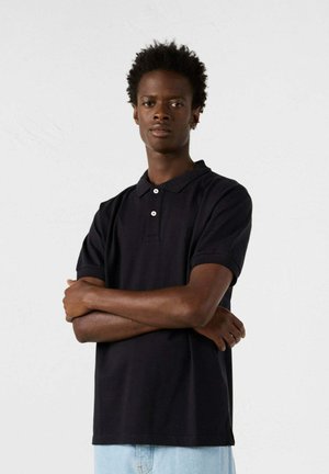 Polo negro de manga corta con cuello, tres botones y un pequeño logo. Diseñado con una tela suave y un ajuste clásico.
