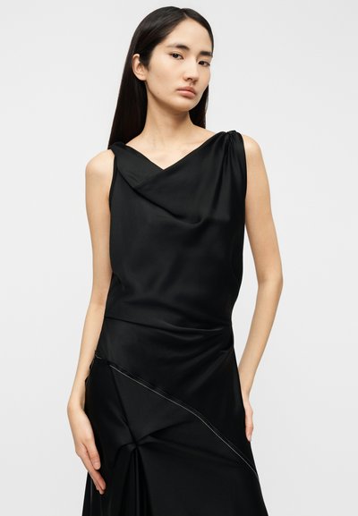 Vestito nero senza maniche con scollo a cascata e design drappeggiato. Presenta una cucitura diagonale con dettagli di cucitura sottili. Tessuto dalla texture liscia.