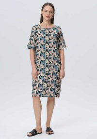Kurzes Kleid mit kurzen Ärmeln, das einen dunklen Hintergrund mit einem bunten Blättermuster zeigt. Hergestellt aus leichtem Stoff mit entspannter Passform und rundem Halsausschnitt.