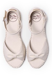 Beige kangas espadrillet med bånddetalje og ankelrem; har kontrasterende søm og en flat såle. Klassisk, minimalistisk design.