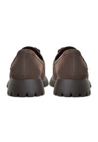 Scarpe in suede marrone con punta arrotondata e suola in gomma nera chunky con un motivo testurizzato. La vista posteriore mostra dettagli cuciti sui lati.