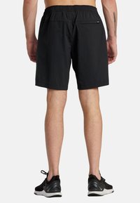 Black swim shorts with an elastic waistband, a rear pocket, and a smooth texture, featuring simple design lines and no visible logos.