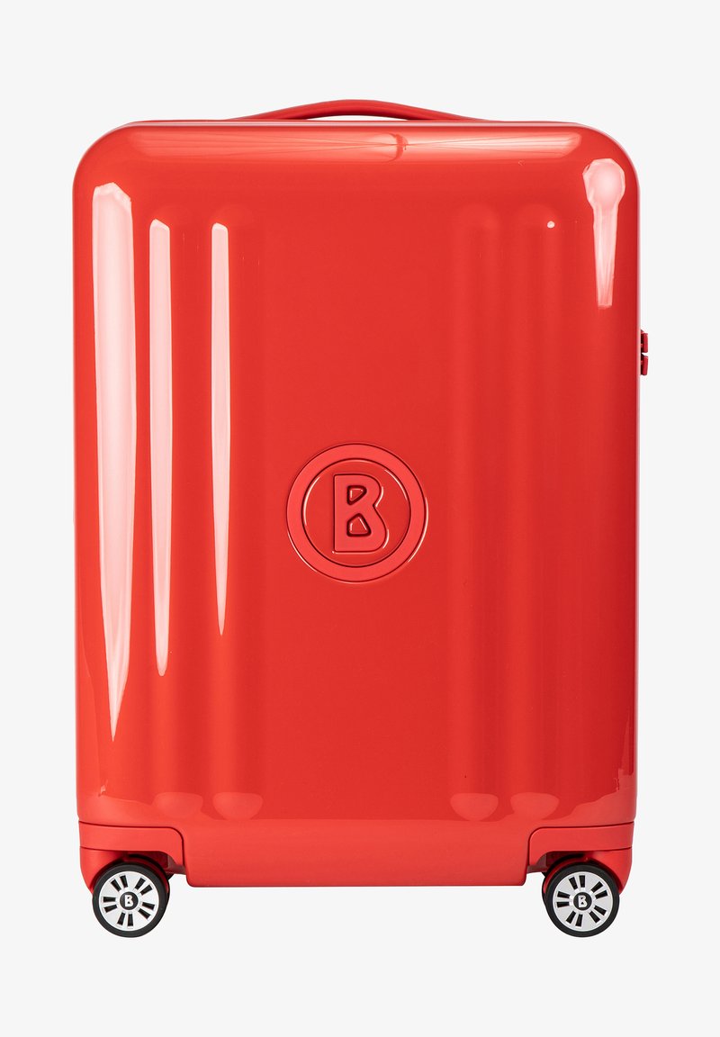 Valigia rigida di colore rosso lucido, caratterizzata da una forma arrotondata, linee verticali texture e doppie ruote con accenti in bianco e nero a contrasto.