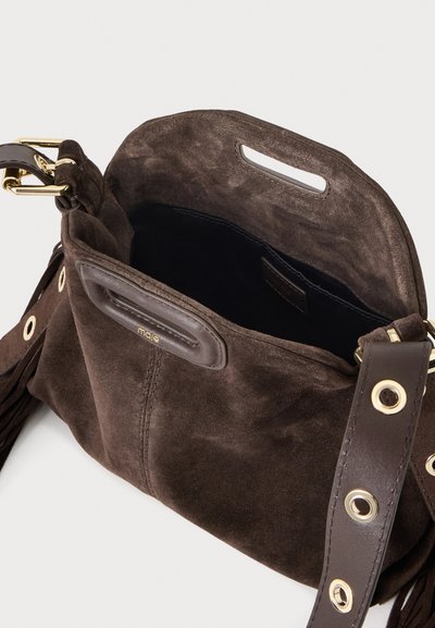 Sac à main en daim marron avec ouverture en haut, bandoulière en cuir avec œillets dorés et détail pompon, et boucle en métal doré.