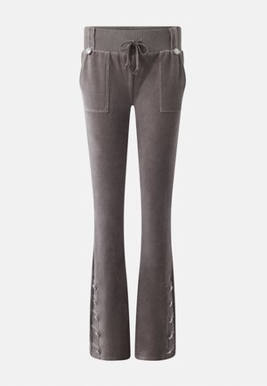 Pilkos spalvos veliūrinės kelnės su gofruota raištelių juosmens dalimi, priekiniu kišenėmis ir sagutomis raištelių detalėmis platėjančiose apačiose.