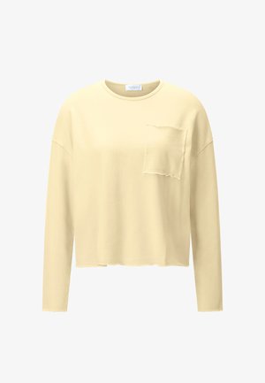 Hosszú ujjú bézs pulóver nyers szegélyekkel és kopott mellzsebbel, kerek nyakkivágással és laza szabással.