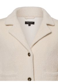 Crème-kleurige wolmix jas met een ingeknipte kraag, twee voorzakken en bruine knopen. Zachte, textuurstof met een relaxte pasvorm.
