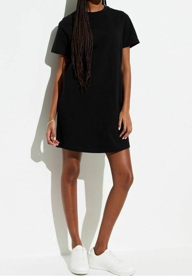 Abito t-shirt in cotone nero con maniche corte e scollo rotondo, caratterizzato da una vestibilità comoda e orlo dritto. Indossato con sneakers bianche.