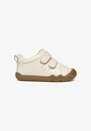 Baskets en cuir blanc avec deux bandes Velcro, semelle en caoutchouc brun et petites perforations sur les côtés pour la respirabilité. Design à bouts ronds.