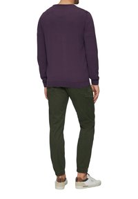 Violeta krūštura krekls pārī ar zaļām kravas biksēm. Bikšu malās ir elastīgas aproces un sānu kabata. Izskatu noslēdz baltas kedas.