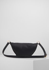 Musta keinonahkainen laukku, jossa on pyöristetty, rakenteellinen muotoilu. Ominaisuuksiin kuuluu sileä pinta, säädettävä olkahihna ja kultasävyiset metalliosat.