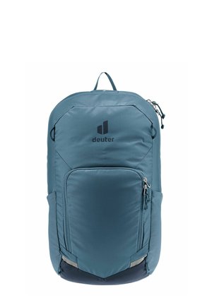 Teal nylon backpack with a front zip pocket, side mesh pocket, logo detail, and reflective accents at the bottom. Features adjustable shoulder straps.