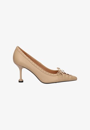 Zapato de piel beige con puntera afilada, que presenta un detalle de cordones en la parte frontal y un tacón delgado con un acento negro redondeado.