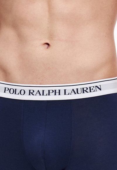 Temno modri bokser hlačke z belim pasom, na katerem je napisano "POLO RALPH LAUREN" v temno modri barvi. Gladek material in oprijeta zasnova.
