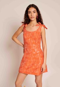 Φλοράλ φόρεμα σε πορτοκαλί απόχρωση, με κορδόνια στους ώμους, κομμένο σώμα και φαρδιά φούστα. Φτιαγμένο από ελαφρύ ύφασμα με λεία υφή.