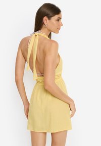 Κίτρινο φόρεμα με halter λαιμόκοψη, ανοιχτή πλάτη, ελαστική μέση και κορδόνια στη λαιμόκοψη. Ελαφρύ ύφασμα με απαλή υφή.