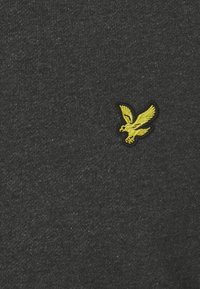 Sweatshirt gris charbon en tissu texturé, avec un logo d'aigle brodé jaune sur le côté gauche.