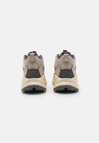 Beżowe i szare sneakersy z teksturowanym wierzchem, z czarnym akcentem na pięcie, amortyzowaną podeszwą i pętlą ułatwiającą zakładanie.