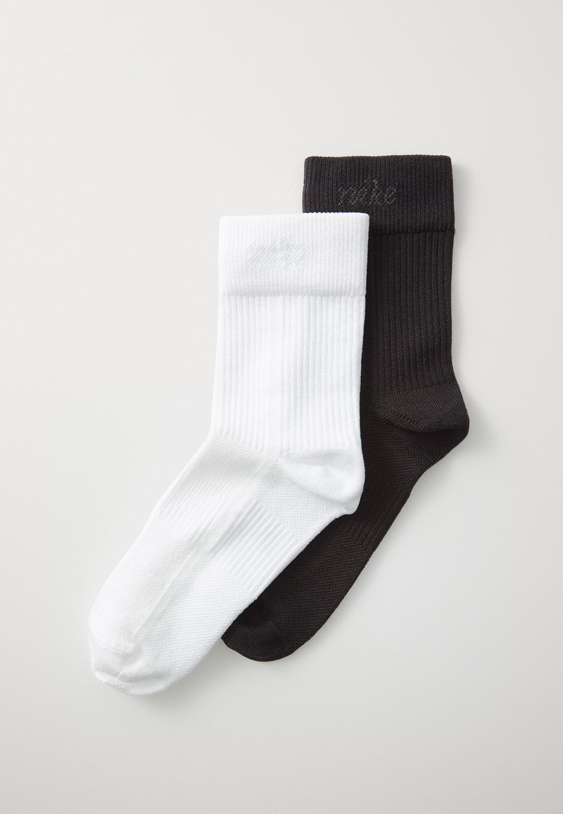 Zwei Paar Socken; ein Paar weiß und eines schwarz. Beide haben eine gerippte Textur und ein kleines Logo am Bund. Typische Sockenform.